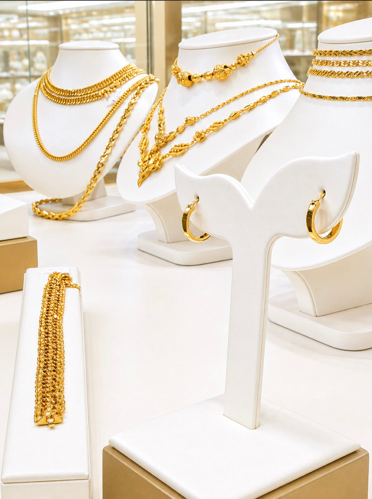 A gold jewelry display with chain necklaces, beaded necklaces, and gold hoop earrings