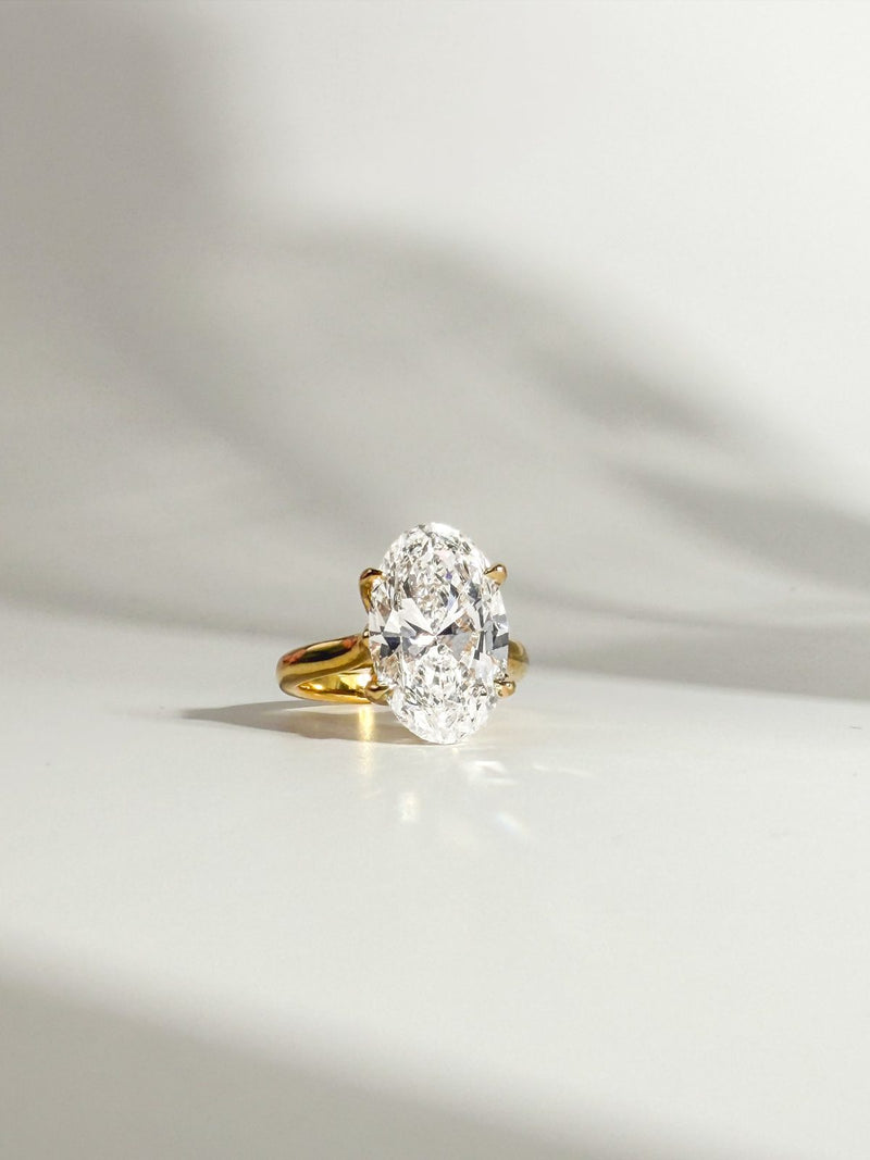 Oval diamond solitaire in yellow gold, side view in soft window shadow